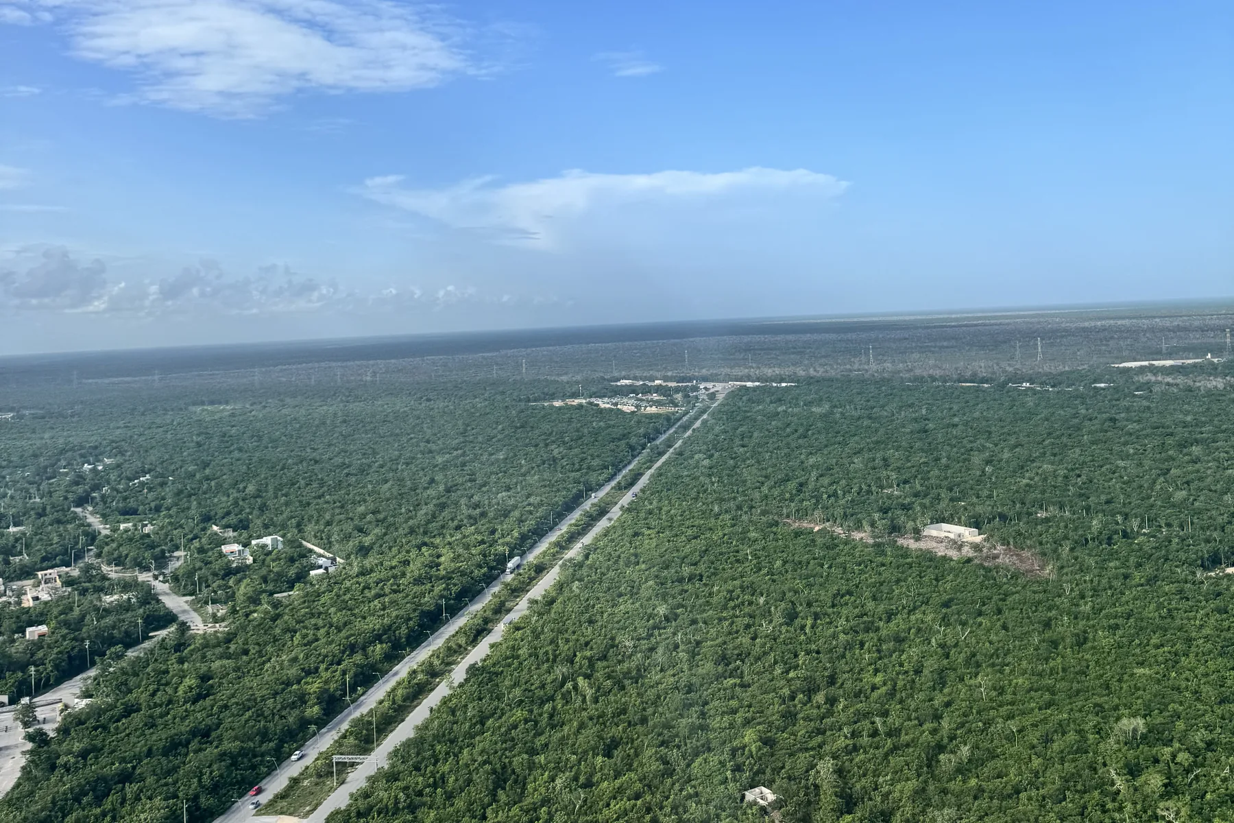 Vista aérea de la carretera cortando la selva hacia lotes despejados, Quintana Roo