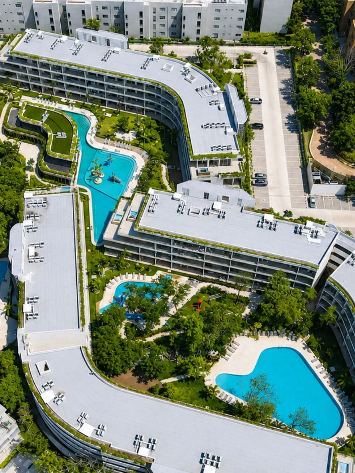 Aerial view of a finished residential development, pools and low-rise buildings surrounded by parking and a street grid
