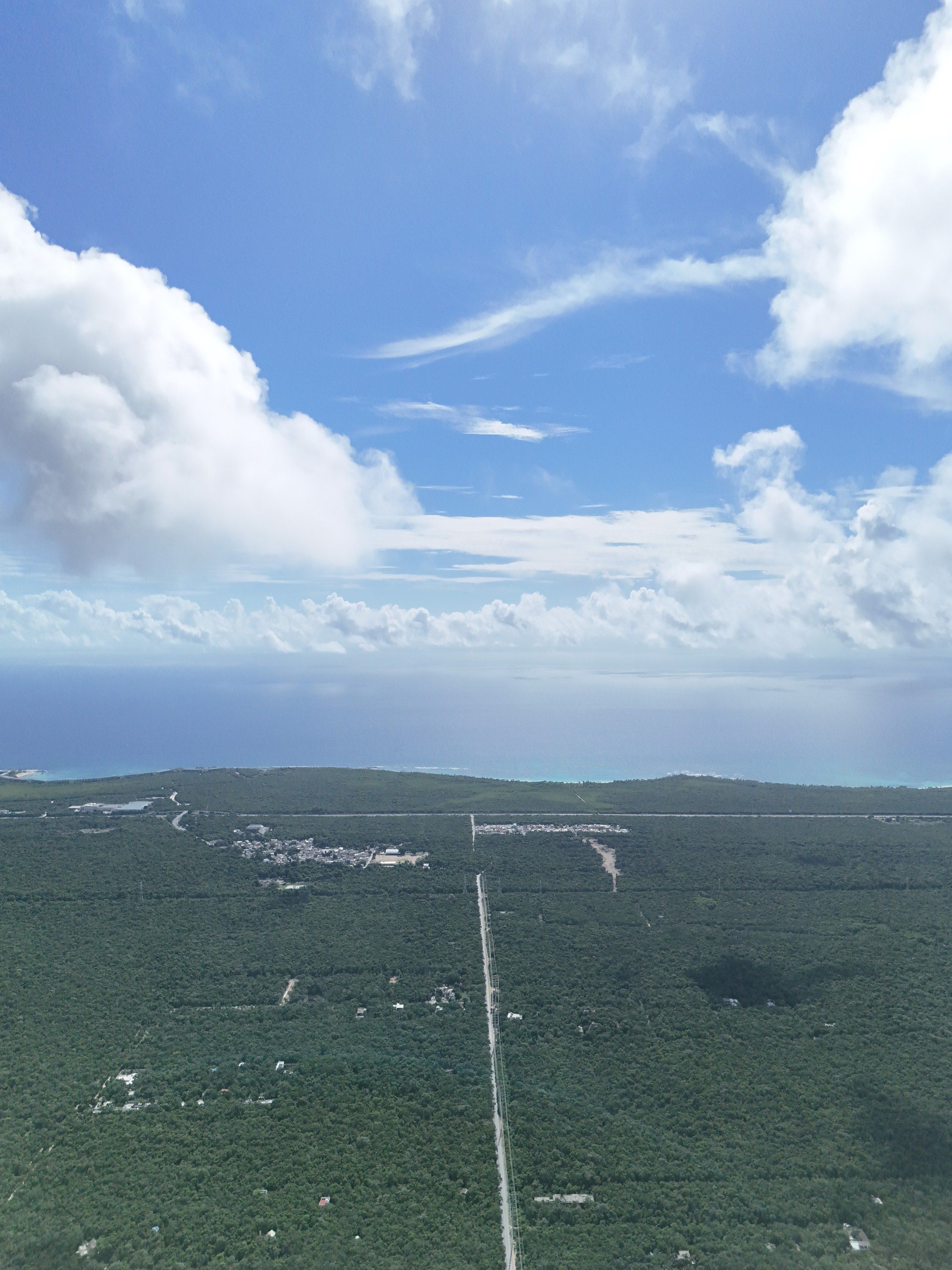 Aerial photograph looking east across unbroken jungle toward the town of Chemuyil and the Caribbean on the horizon