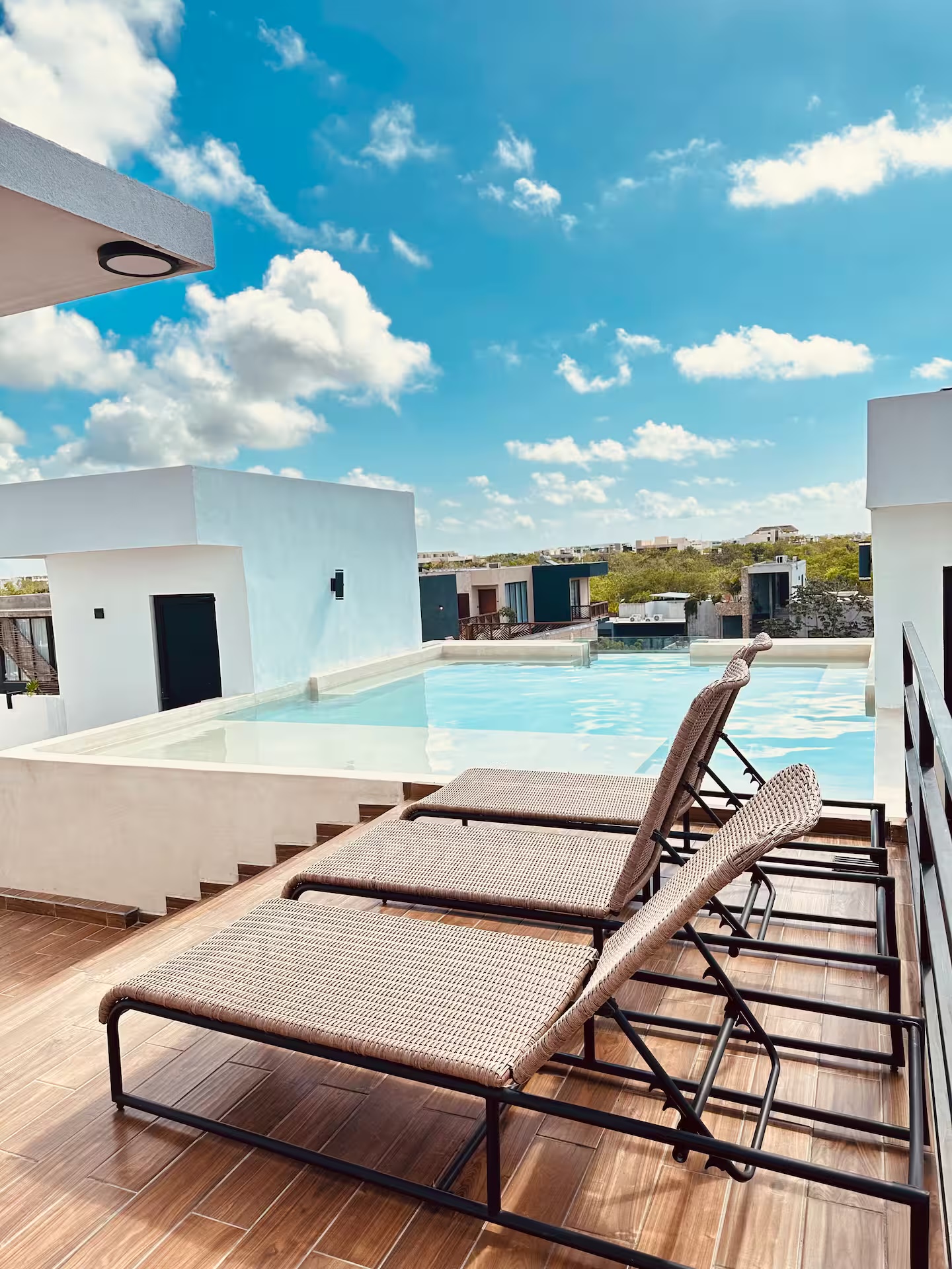 Rooftop pool at Naia Naay Village with lounge chairs and jungle skyline
