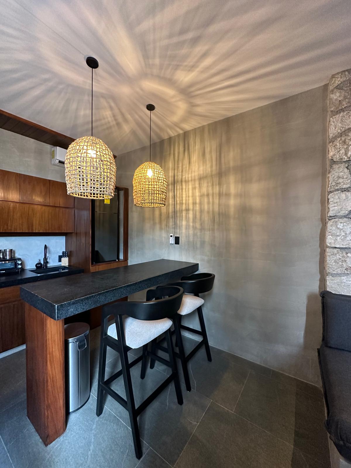 Kitchen and bar seating inside Siwa Tulum B2-101, with woven pendant lighting