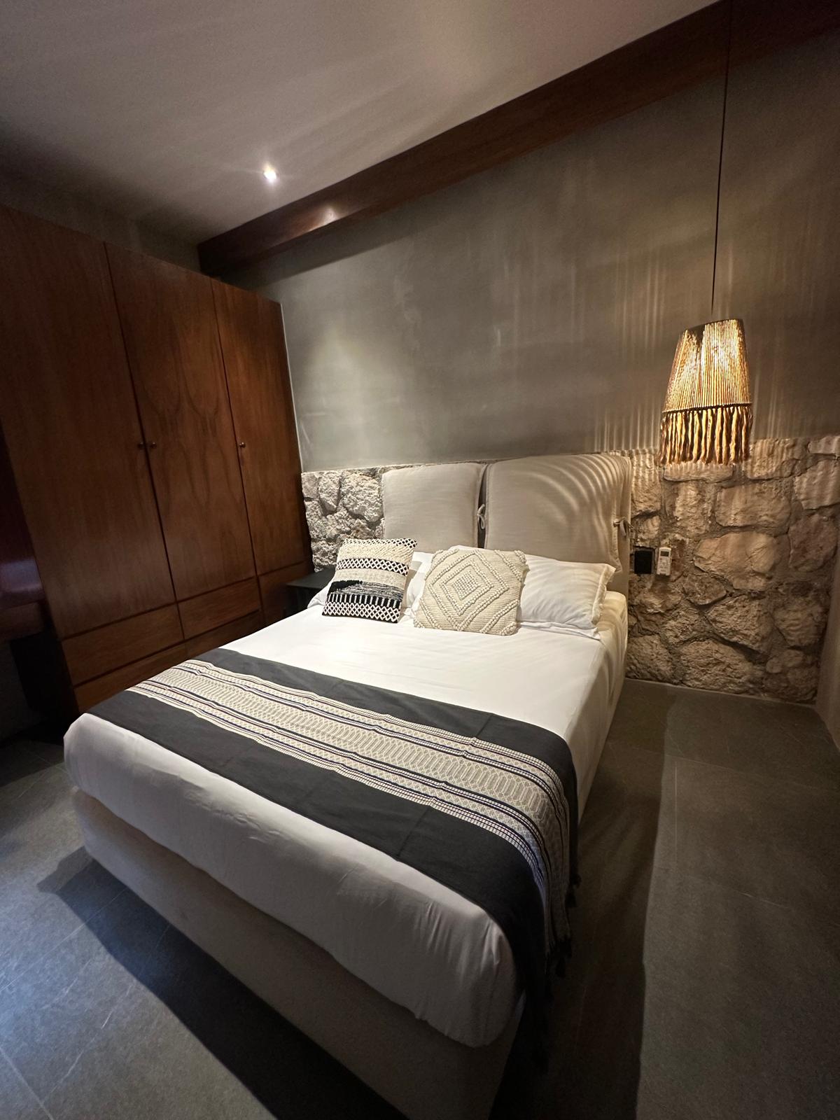 Bedroom of Siwa Tulum B2-101 with a stone-clad headboard wall