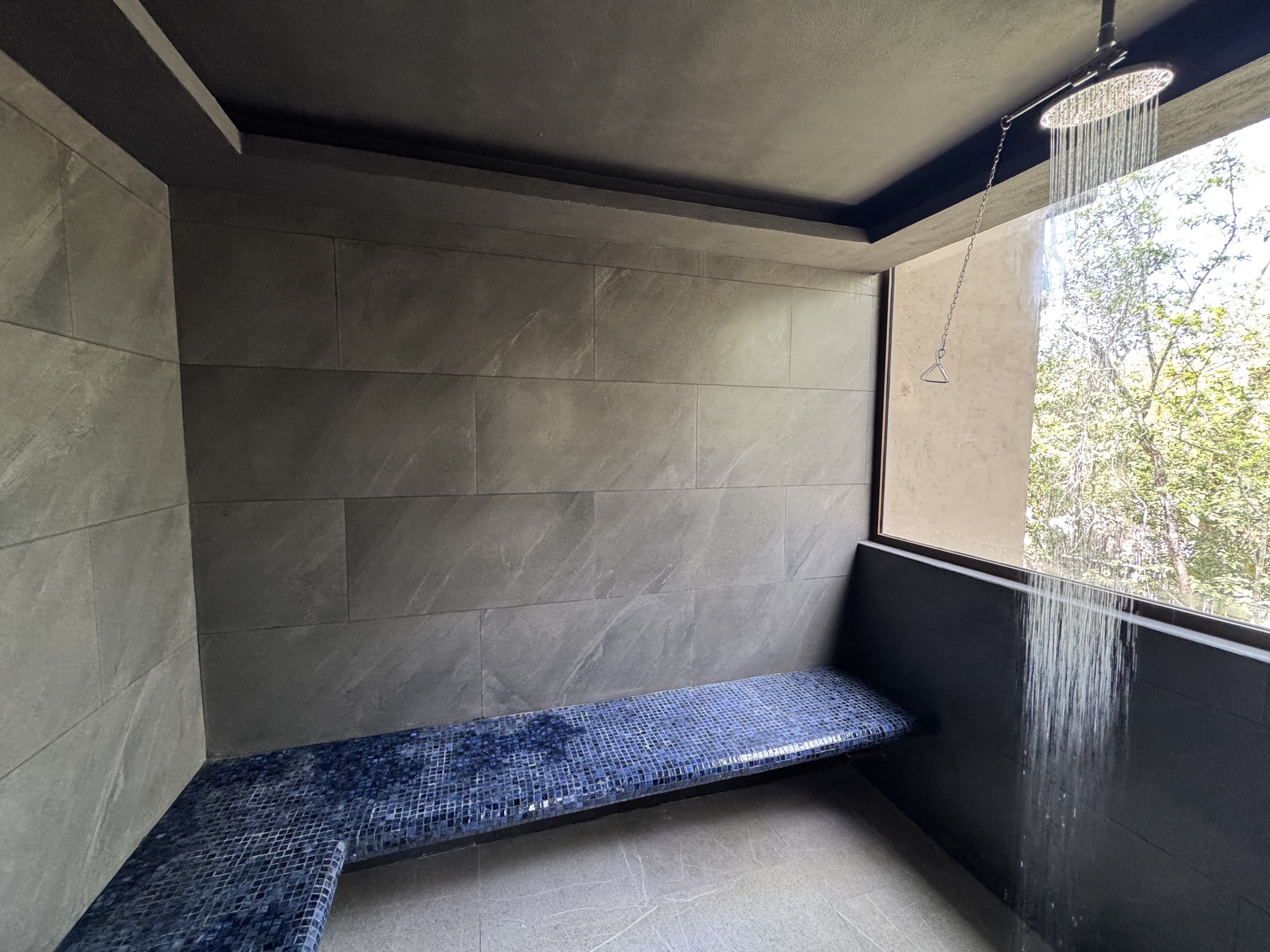 Outdoor rain-shower room finished in dark stone at Siwá Élevé