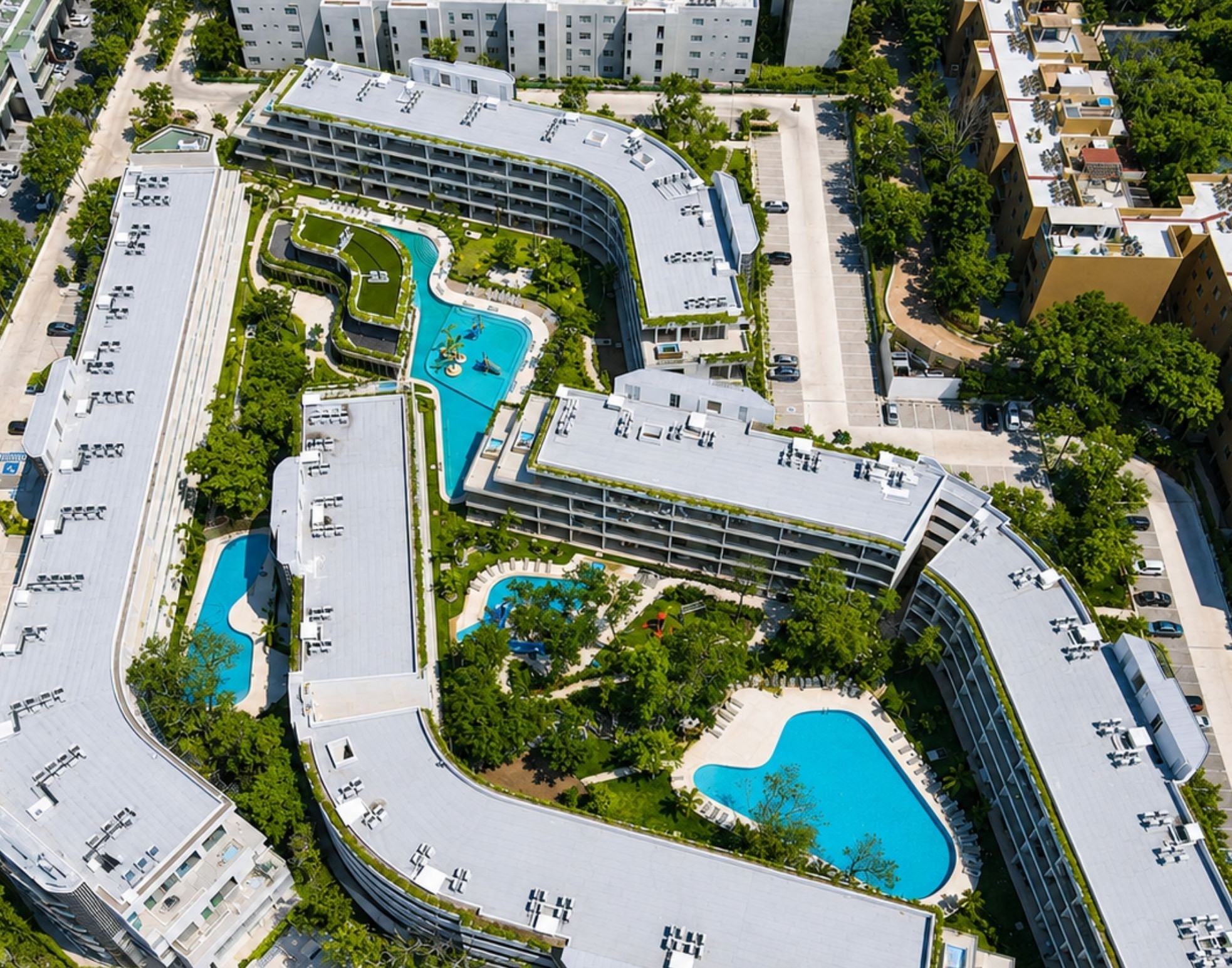Aerial view of the four curved towers and pools of The Leaf Condos Playacar inside Playacar Fase II