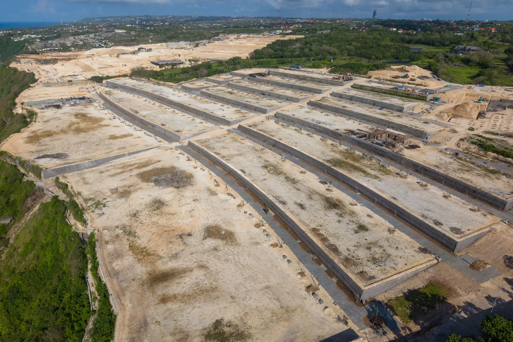 Aerial view of a large site graded into terraces with concrete retaining walls and access roads laid out, no buildings on it yet